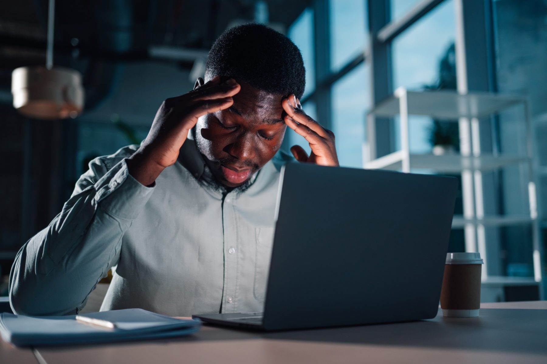 An engineer working alone late at night, lit by a screen.