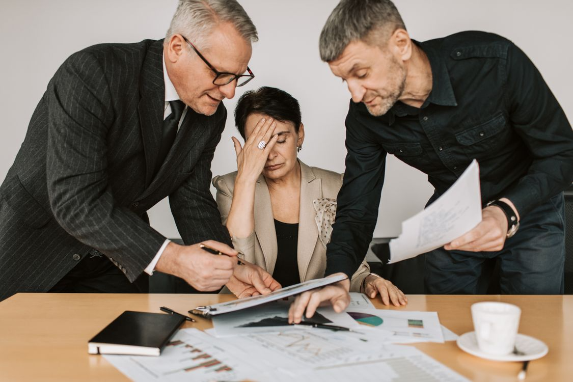 Three leaders poring over reports, one with her head in her hand
